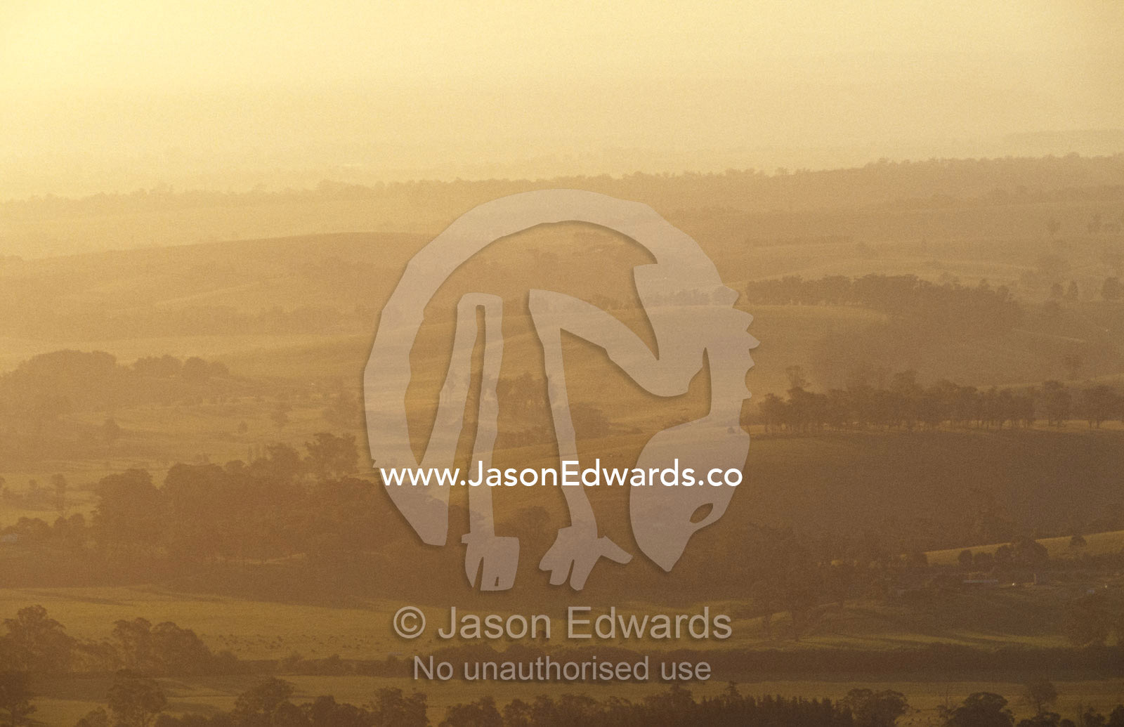 A hazy sunset over picturesque fields and rolling hills. Mt Raymond, Victoria, Australia.