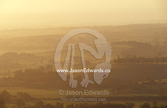 A hazy sunset over picturesque fields and rolling hills. Mt Raymond, Victoria, Australia.