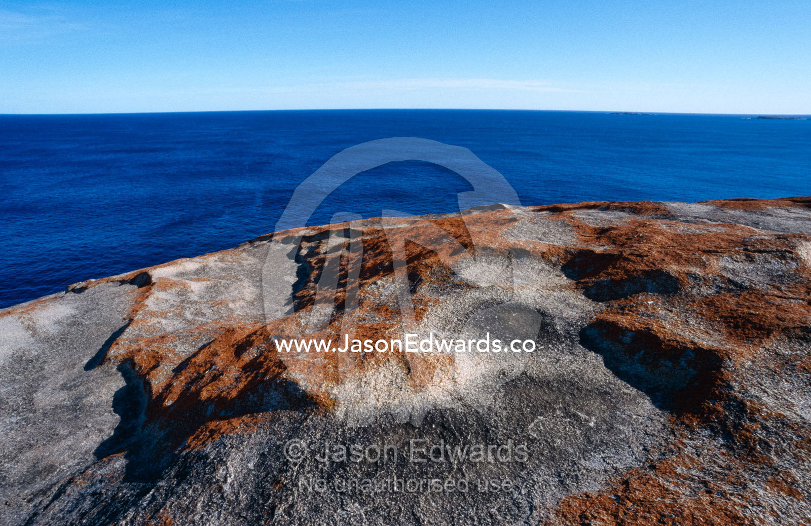 Orange Lichen on coastal granite rocks overlooks a vast ocean. Kangaroo Island, South Australia.