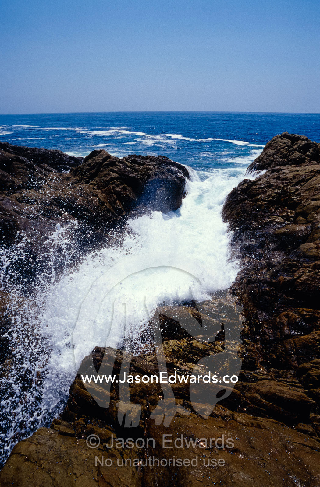 Ocean waves crashing onto rocks flow inland causing erosion. Tathra, New South Wales, Australia.