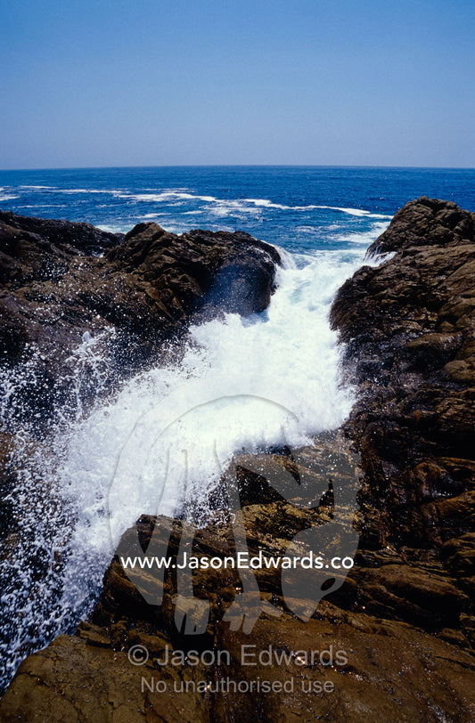 Ocean waves crashing onto rocks flow inland causing erosion. Tathra, New South Wales, Australia.