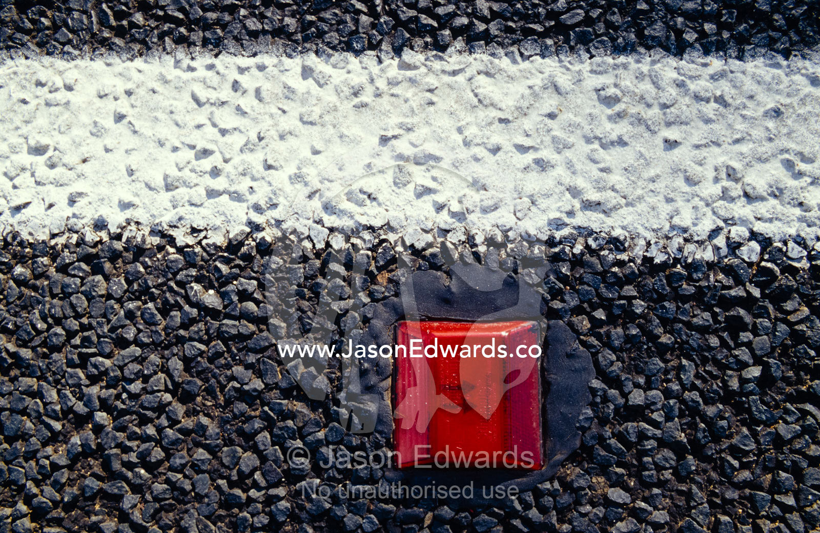 A white line and red reflective marker set into the road bitumen. Coonabarrabran, New South Wales, Australia.