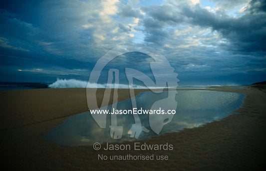 Waves break beyond the reach of a pool stranded by the receding tide. Warrnambool, Victoria, Australia.