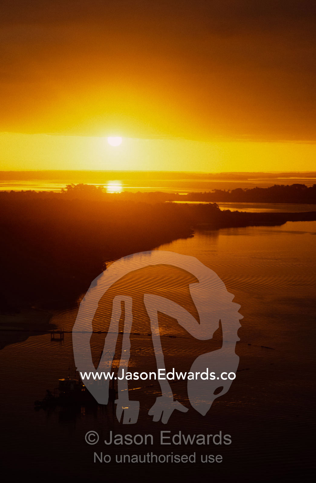 An ocean channel weaving past a sand dredge at sunset. Lakes Entrance, Victoria, Australia.