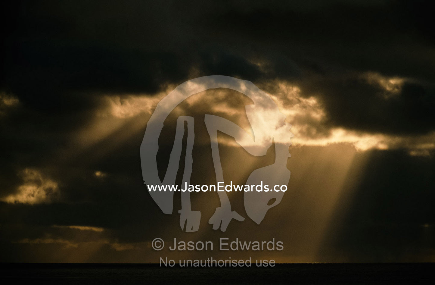 Sun rays pierce a storm front over the open ocean. Cape Range National Park, Western Australia.
