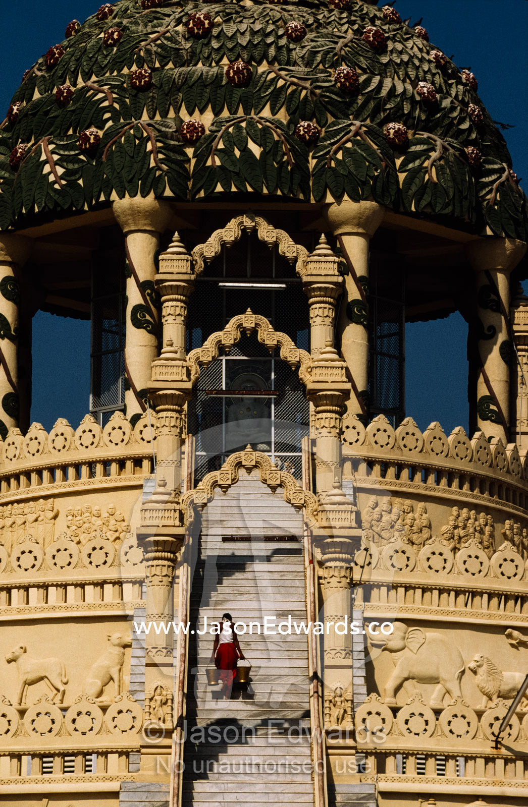 A water bearer walks up the long stairway of a Jain temple. Palitana, India.