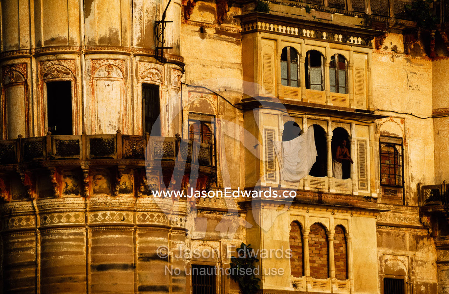 A pilgrim standing in a ghat window, greets the day. Varanasi (Benares), India.