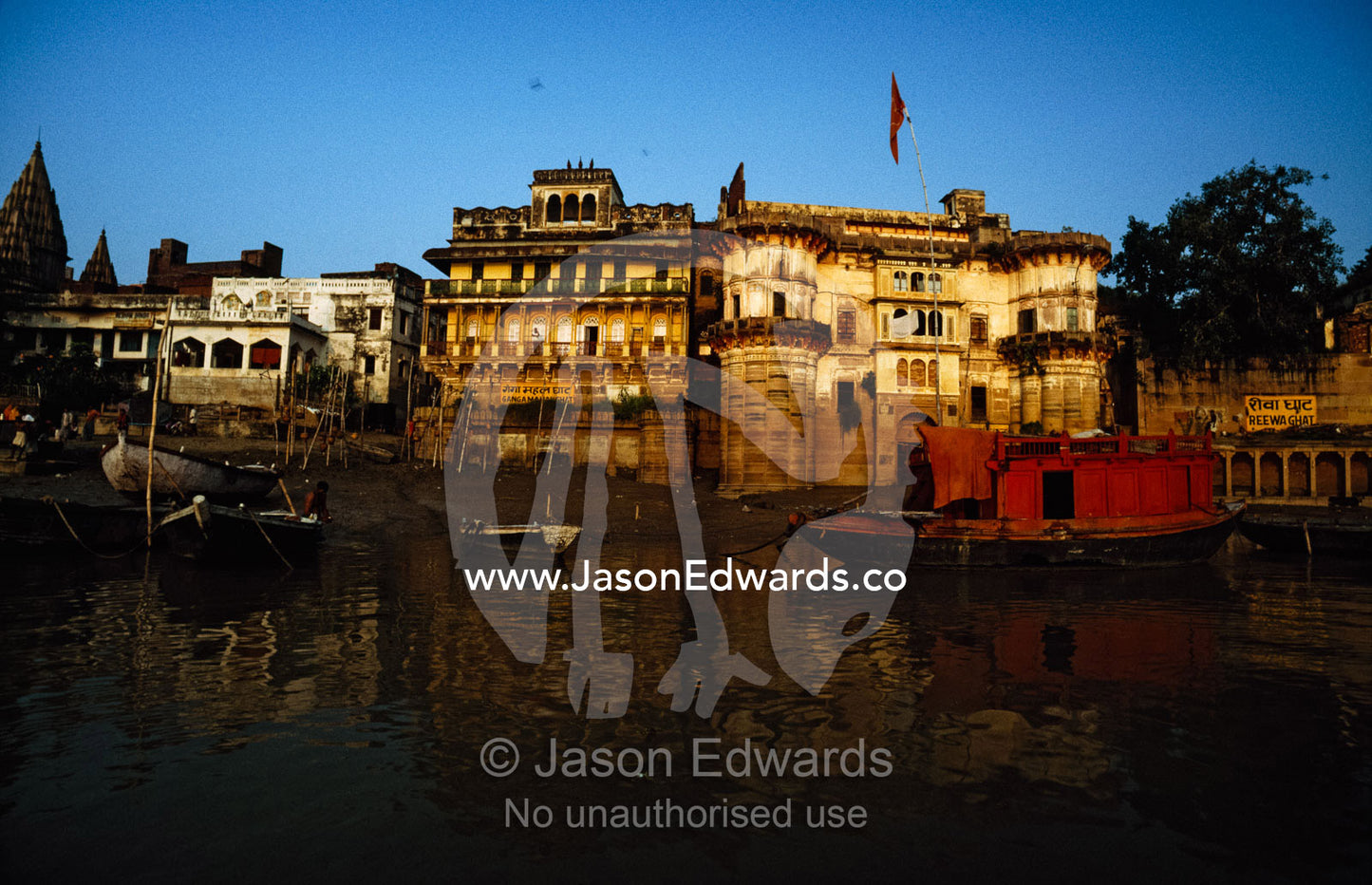 A house boat on the Ganges River sails past the ghat at dawn. Varanasi (Benares), India.