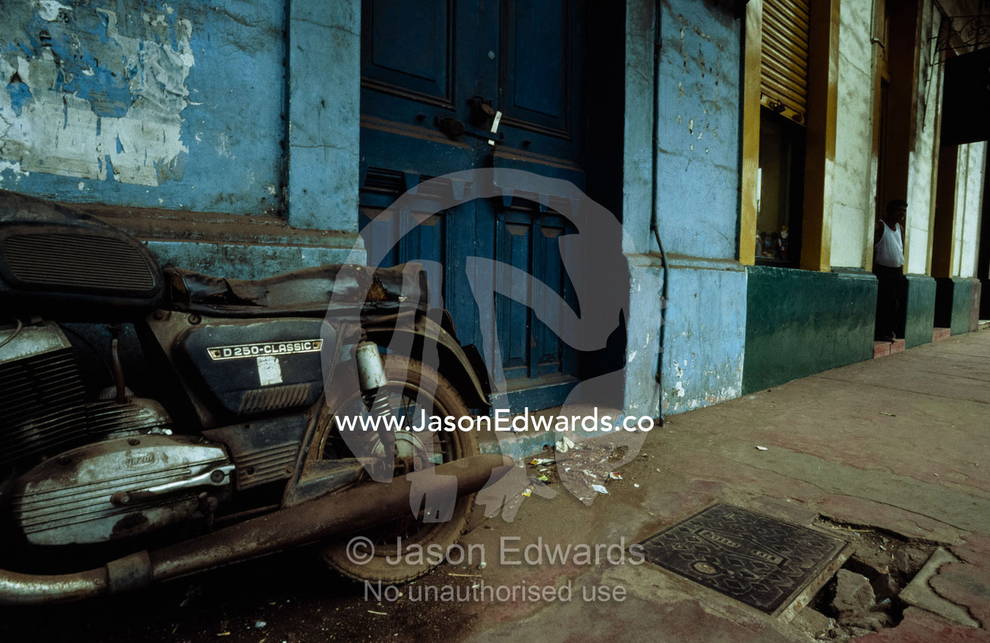 An old motorcycle leans against a dilapidated building. Goa, India.