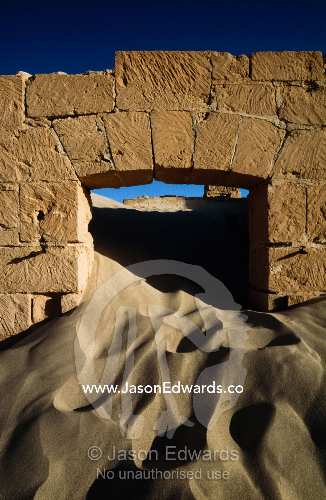 Sand pours through an old telegraph station doorway. Eucla, Western Australia.