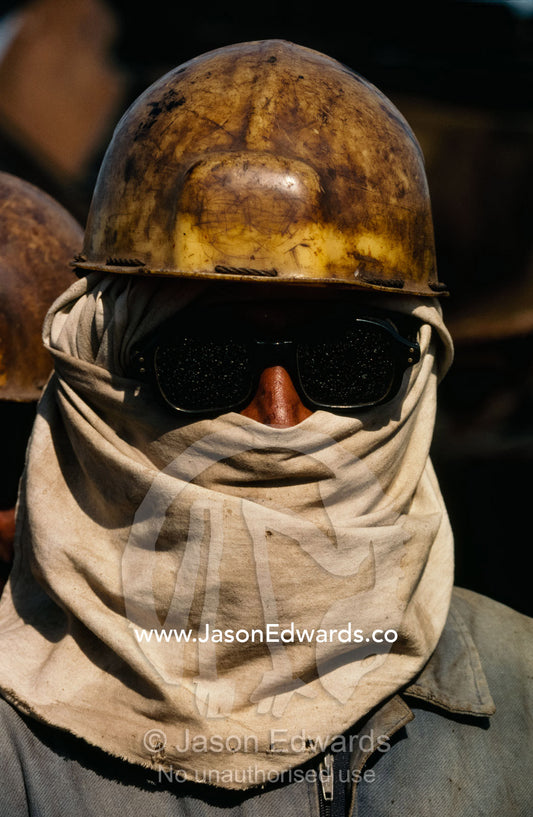 Close up of a laborer in a hard hat at a ship breaking yard. Alang Ship Breaking Yards, Gujarat State, India.