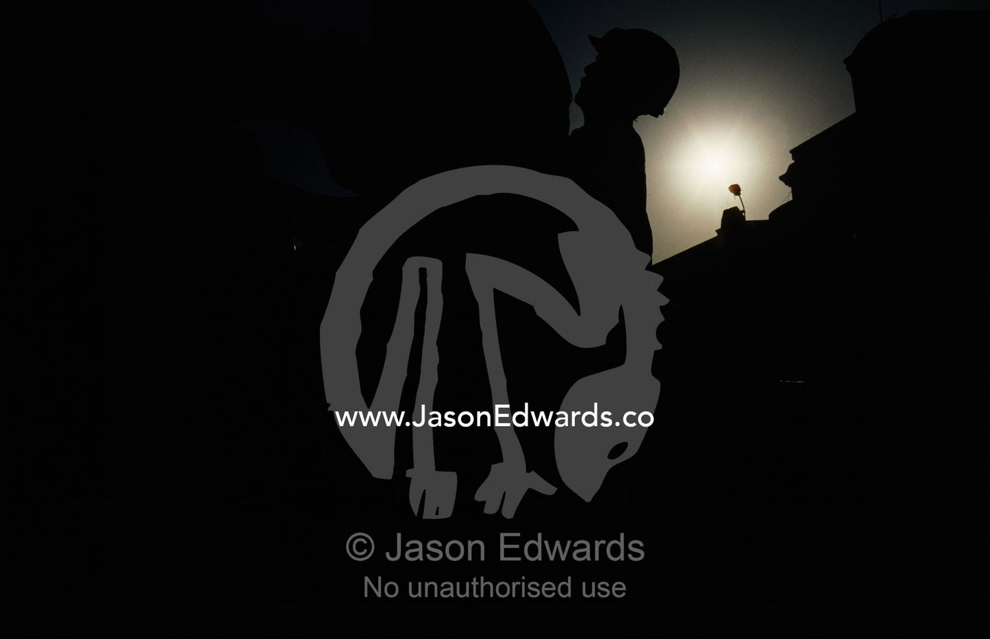 Silhouetted backlit view of a laborer loading steel into a truck. Alang Ship Breaking Yards, Gujarat State, India.