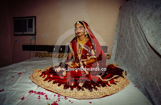 A bride in a red and gold silk sari awaits her wedding ceremony. Sawai Madhopur, Rajasthan State, India.