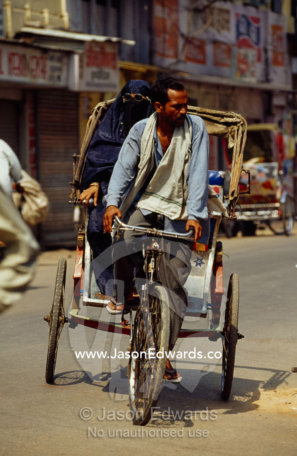 A rickshaw driver with a  Muslim woman passenger. Varanasi (Benares), India.