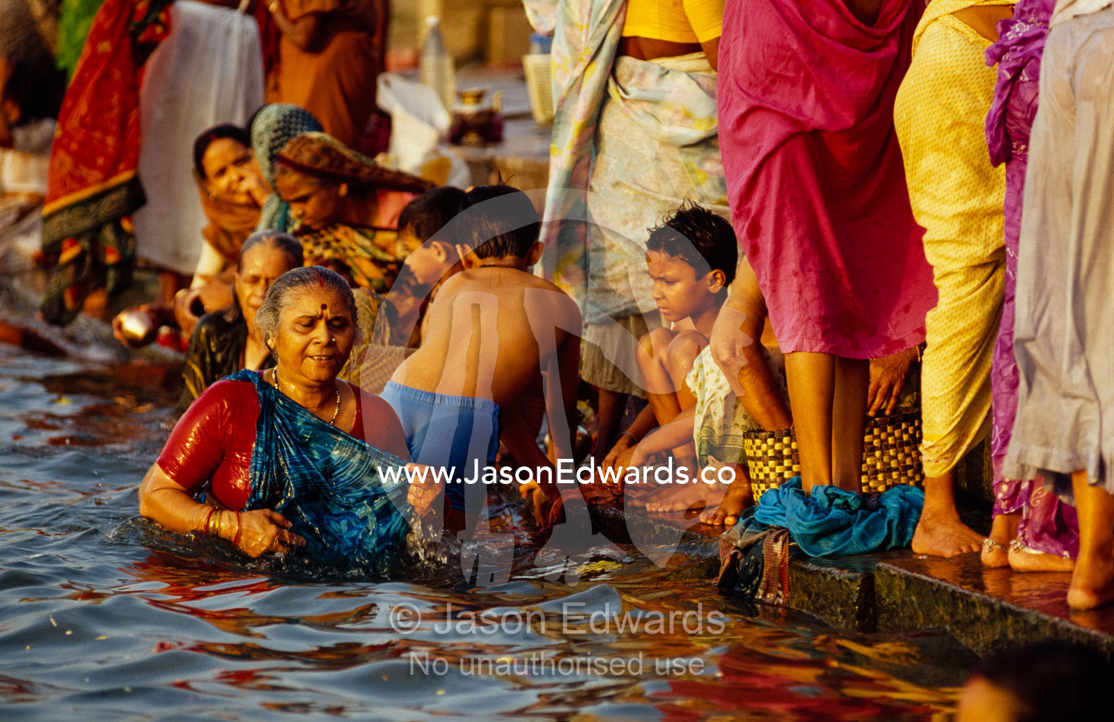 Women and their sons bathe in the Ganges River to remove sins. Varanasi (Benares), India.