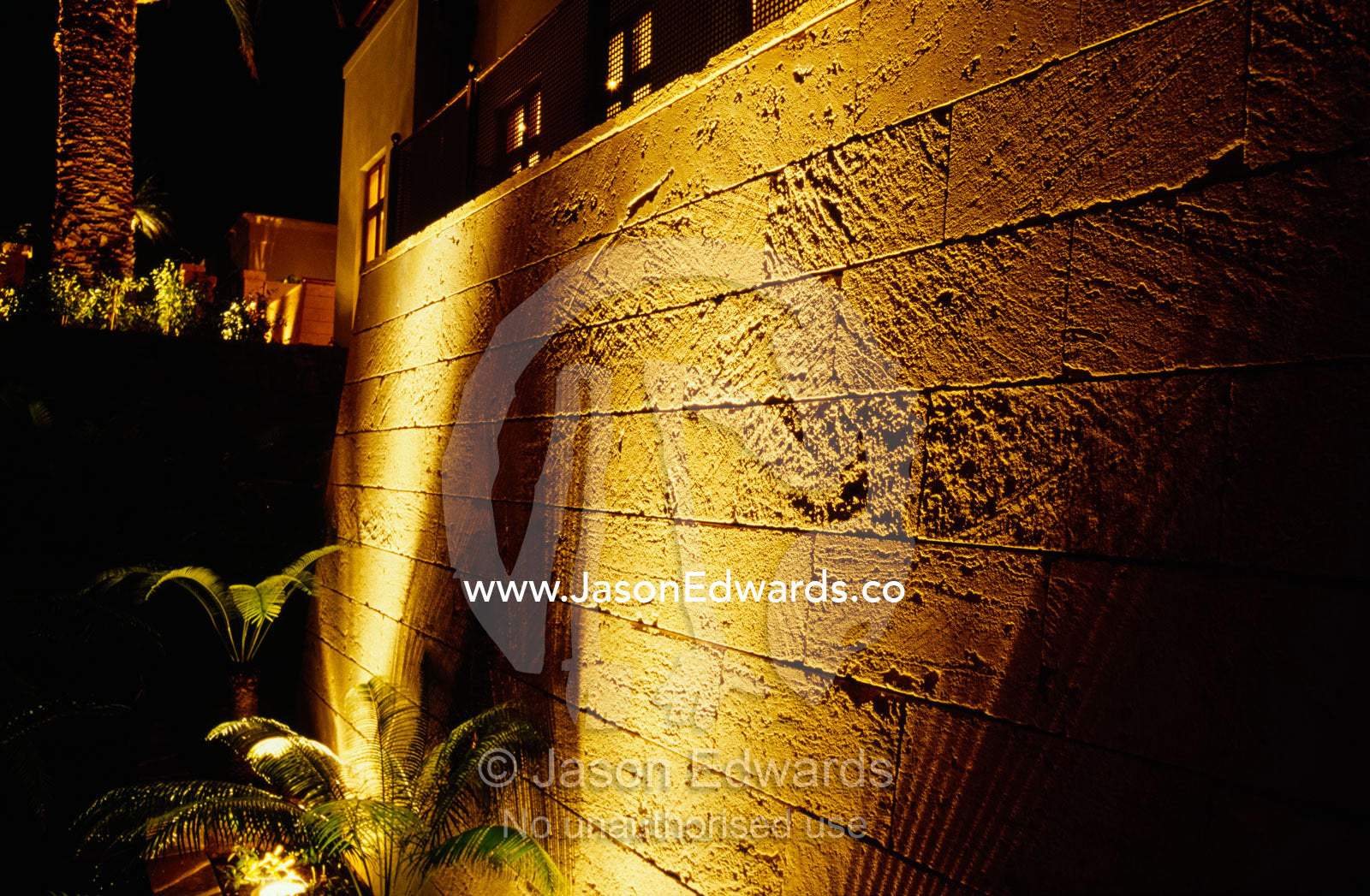 Garden lighting casts a scallop-shaped shadow on a sandstone wall. Toorak, Victoria, Australia.