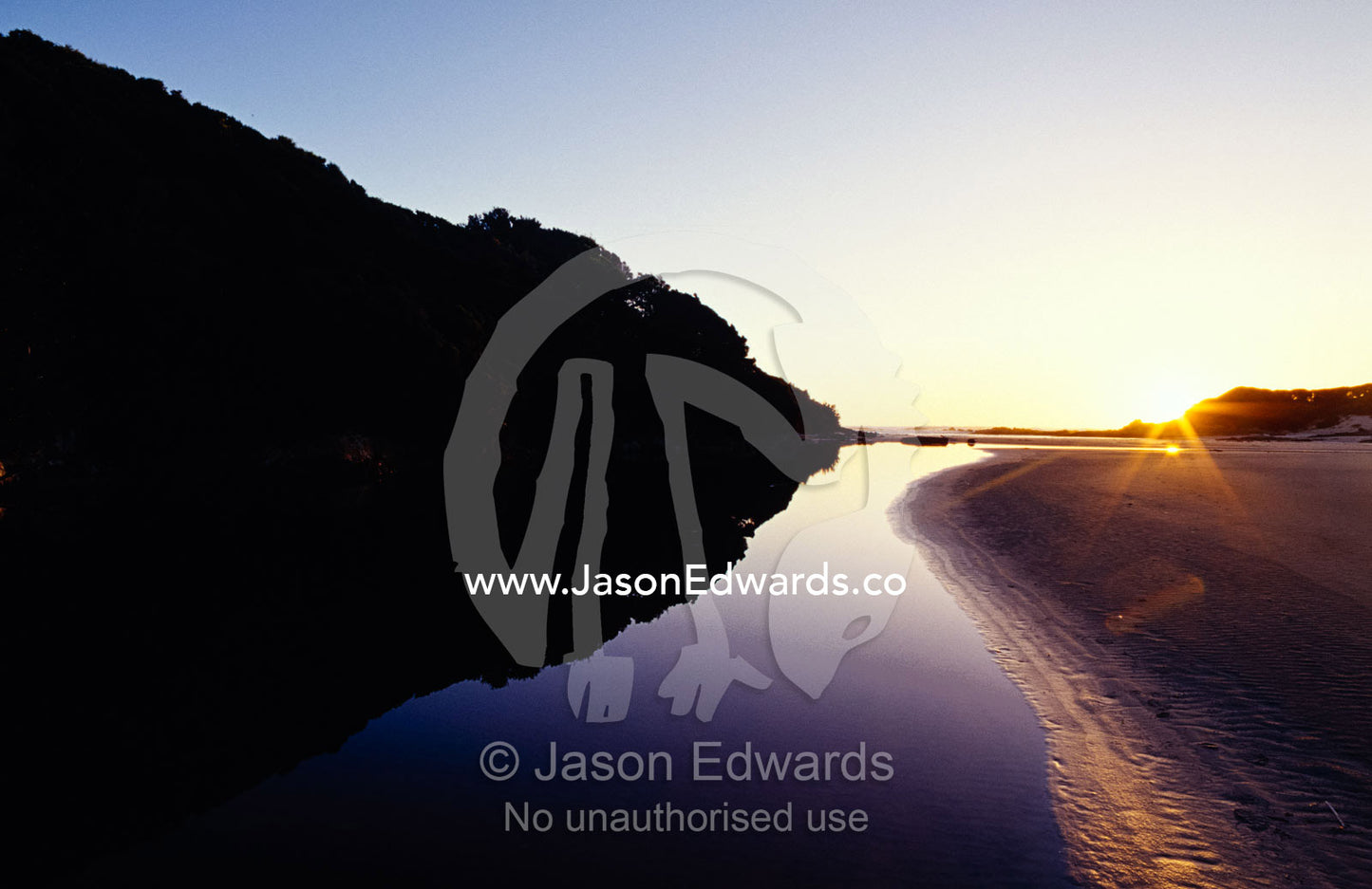 Sunset falls over a tannin stained freshwater lagoon on a remote coast South West Conservation Area Tasmania, Australia.