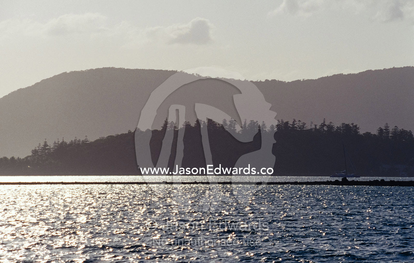 Small tropical islands covered in pine forest silhouetted at sunset. Whitsunday Islands, Queensland, Australia.