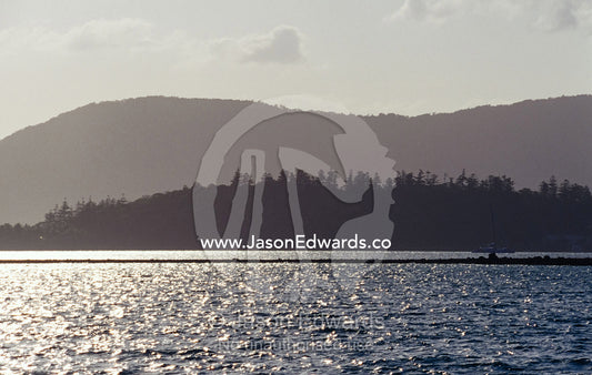 Small tropical islands covered in pine forest silhouetted at sunset. Whitsunday Islands, Queensland, Australia.