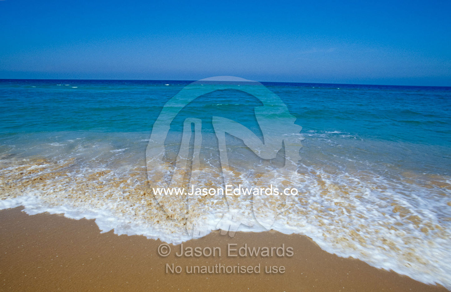 A deep blue sea and crisp waves lap the shoreline of the 90 Mile Beach The Lakes National Park, Victoria, Australia.