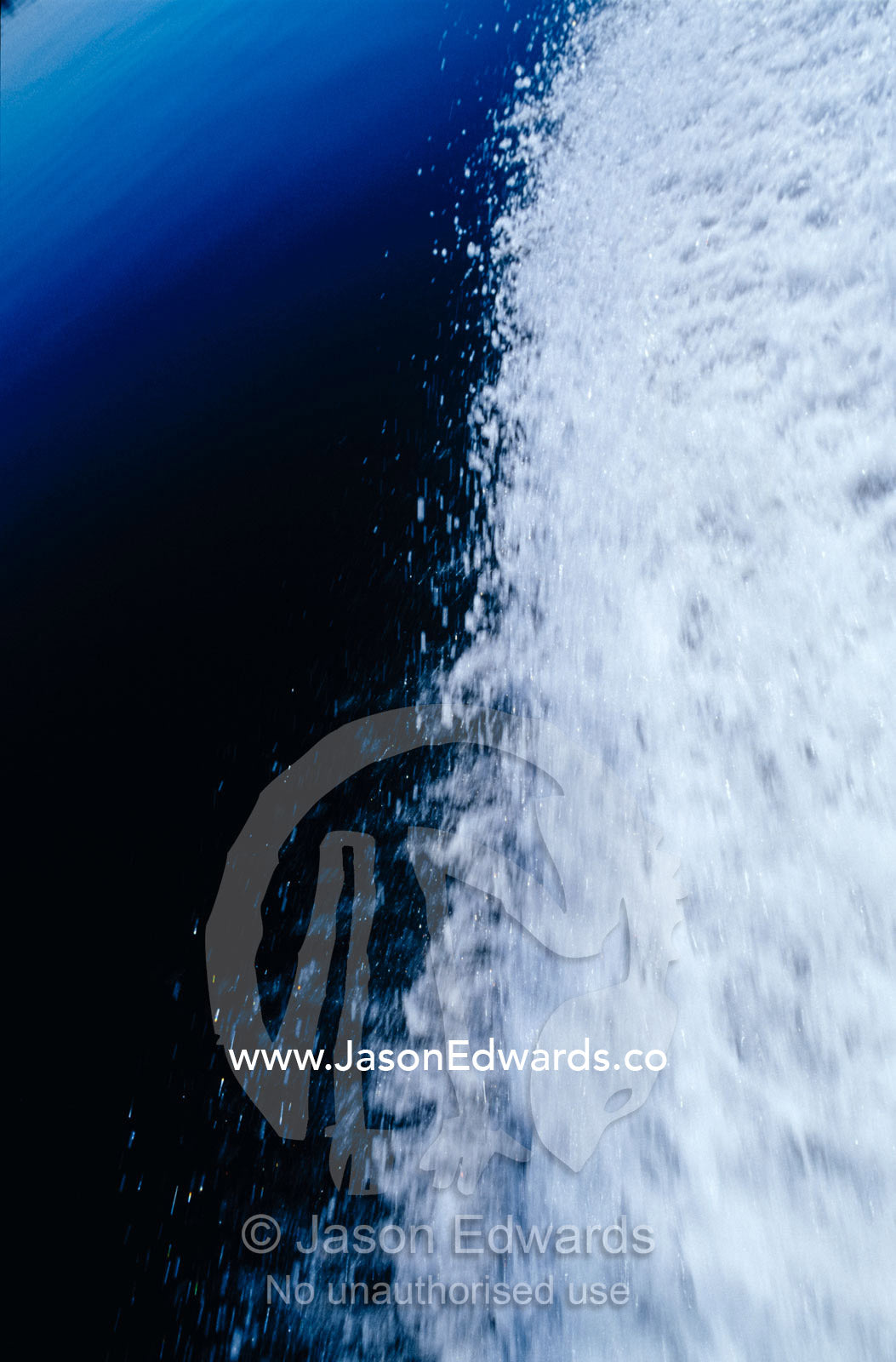 A white foamy motor boat wake pulses on a still lake surface. The Lakes National Park, Victoria, Australia.