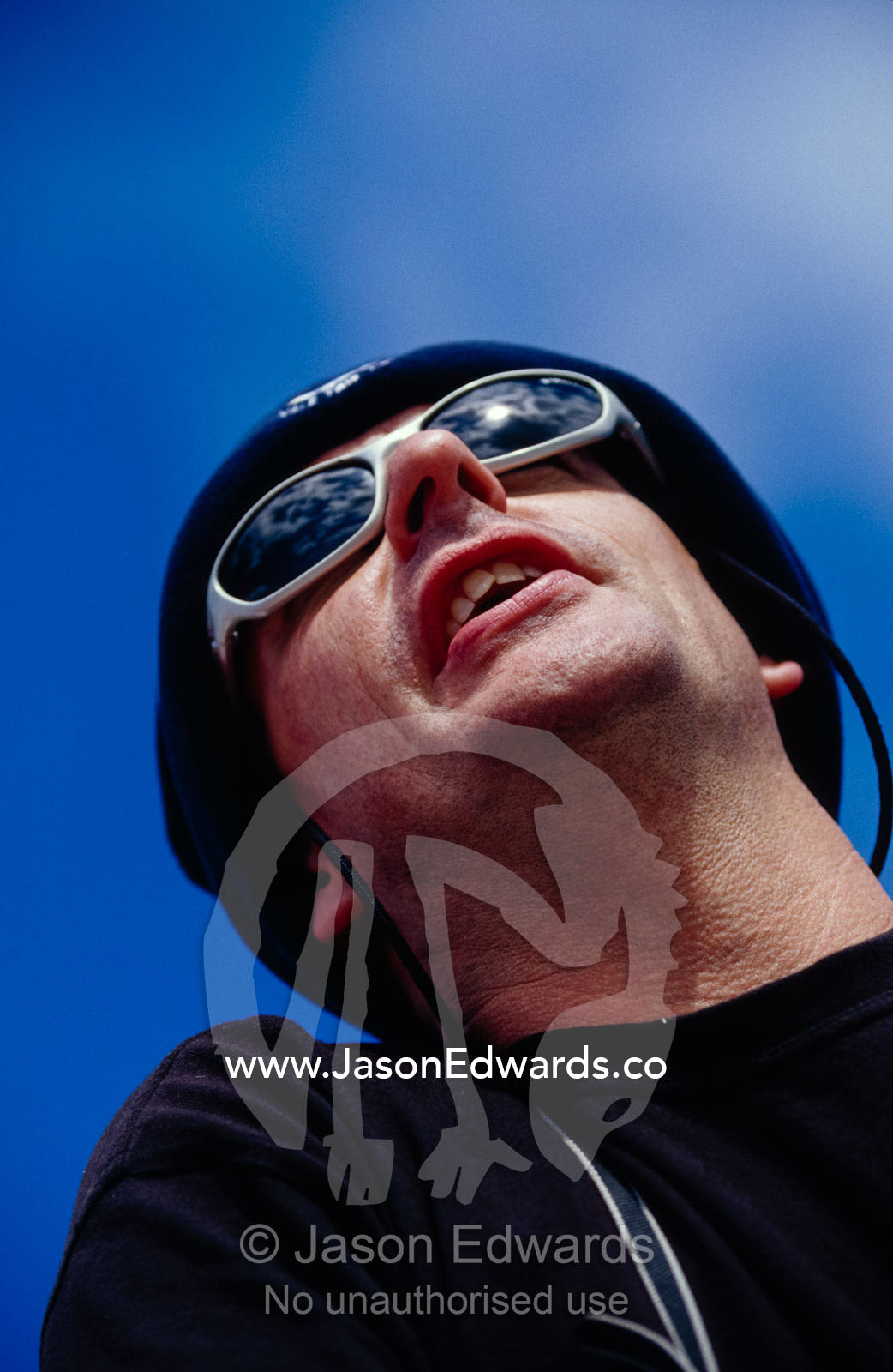 A man wears sun glasses and a woollen hat whilst on a boat at sea. Two Fold Bay, Eden, New South Wales, Australia.