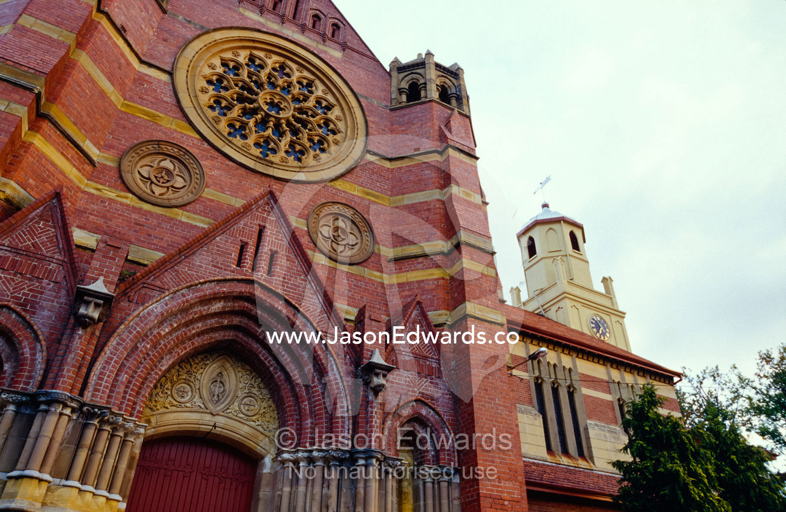 A Christian church facade with ornate brick work and heavy doors. Launceston, Tasmania, Australia.