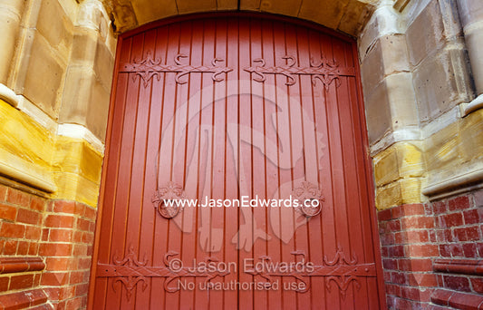A Christian church facade with ornate brick work and heavy doors. Launceston, Tasmania, Australia.