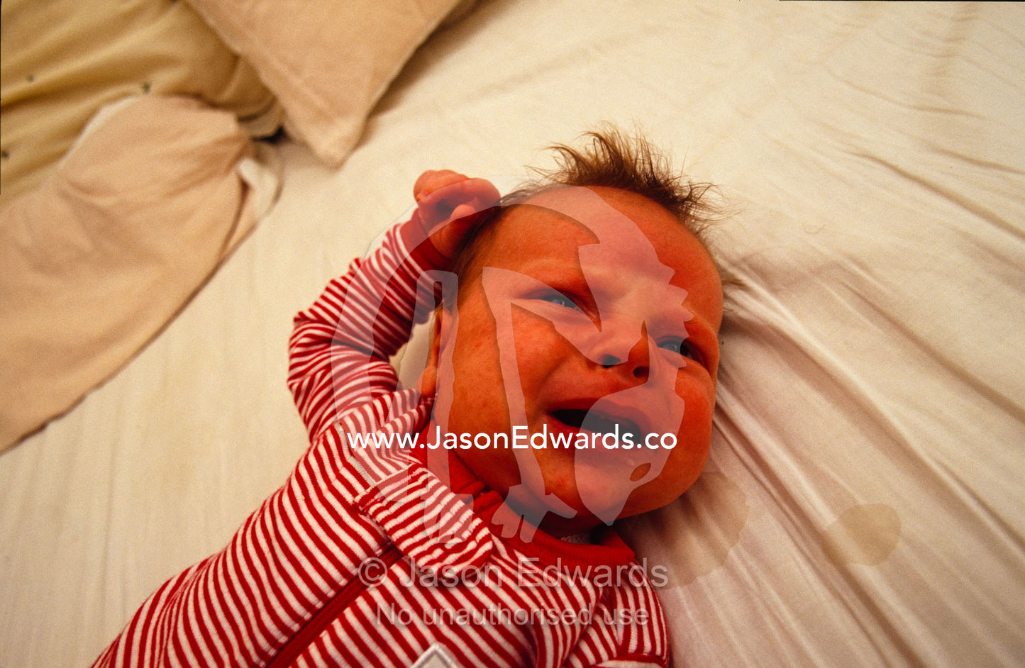 A one month old baby hungry and a little frustrated lying on a bed. North Carlton, Victoria, Australia.