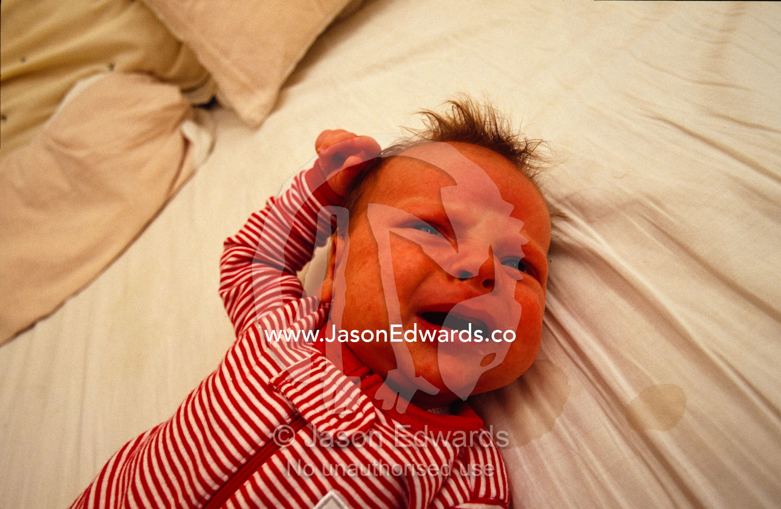 A one month old baby hungry and a little frustrated lying on a bed. North Carlton, Victoria, Australia.