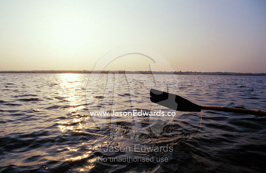 An oar rowing a boat along the holy Ganges River at dawn. Varanasi, Uttar Pradesh, India.