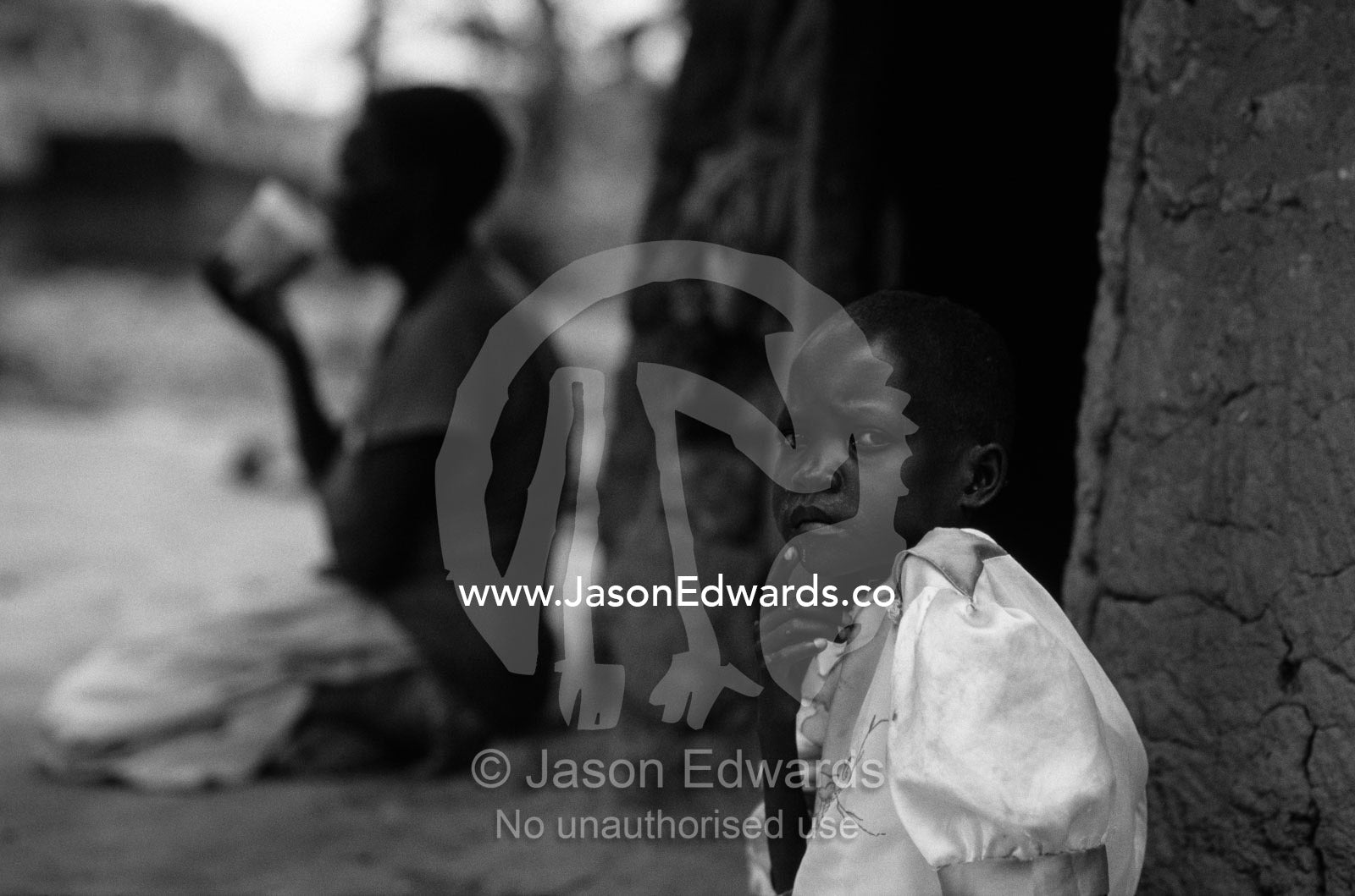 An orphaned African girl with her grandmother and their thatched hut. Tororo District, Uganda.