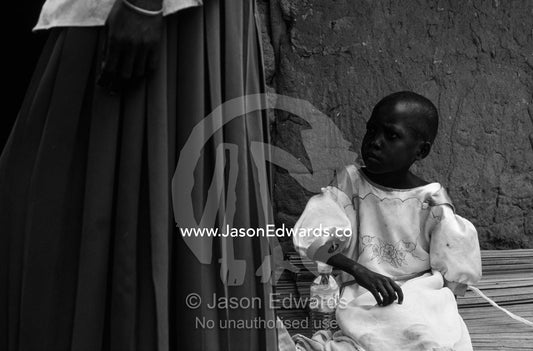 An orphaned African girl with her grandmother and their thatched hut. Tororo District, Uganda.