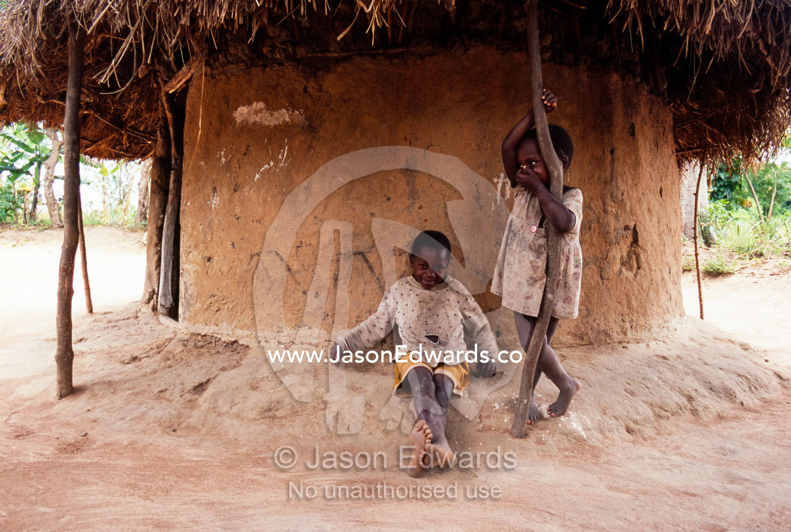 Village children rest in the shade of a hut from the afternoon heat. Tororo District, Uganda.