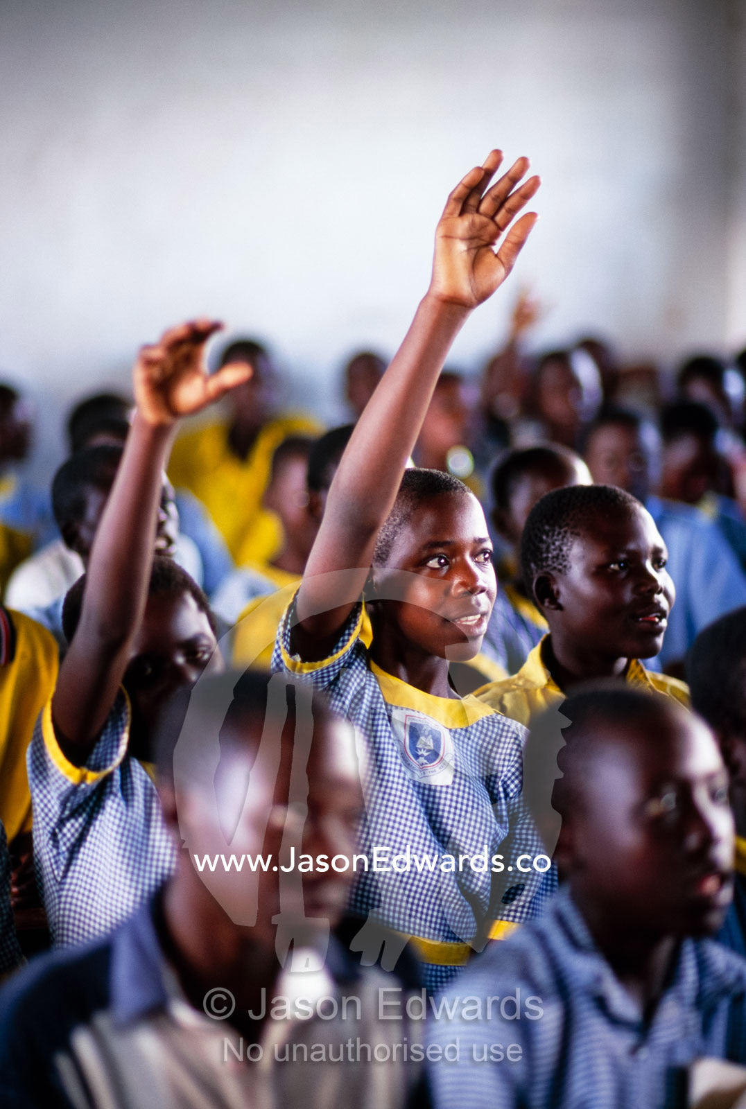 Schoolgirls raise hands to answer questions about preventing AIDS. Tororo Prison School, Tororo District, Uganda.