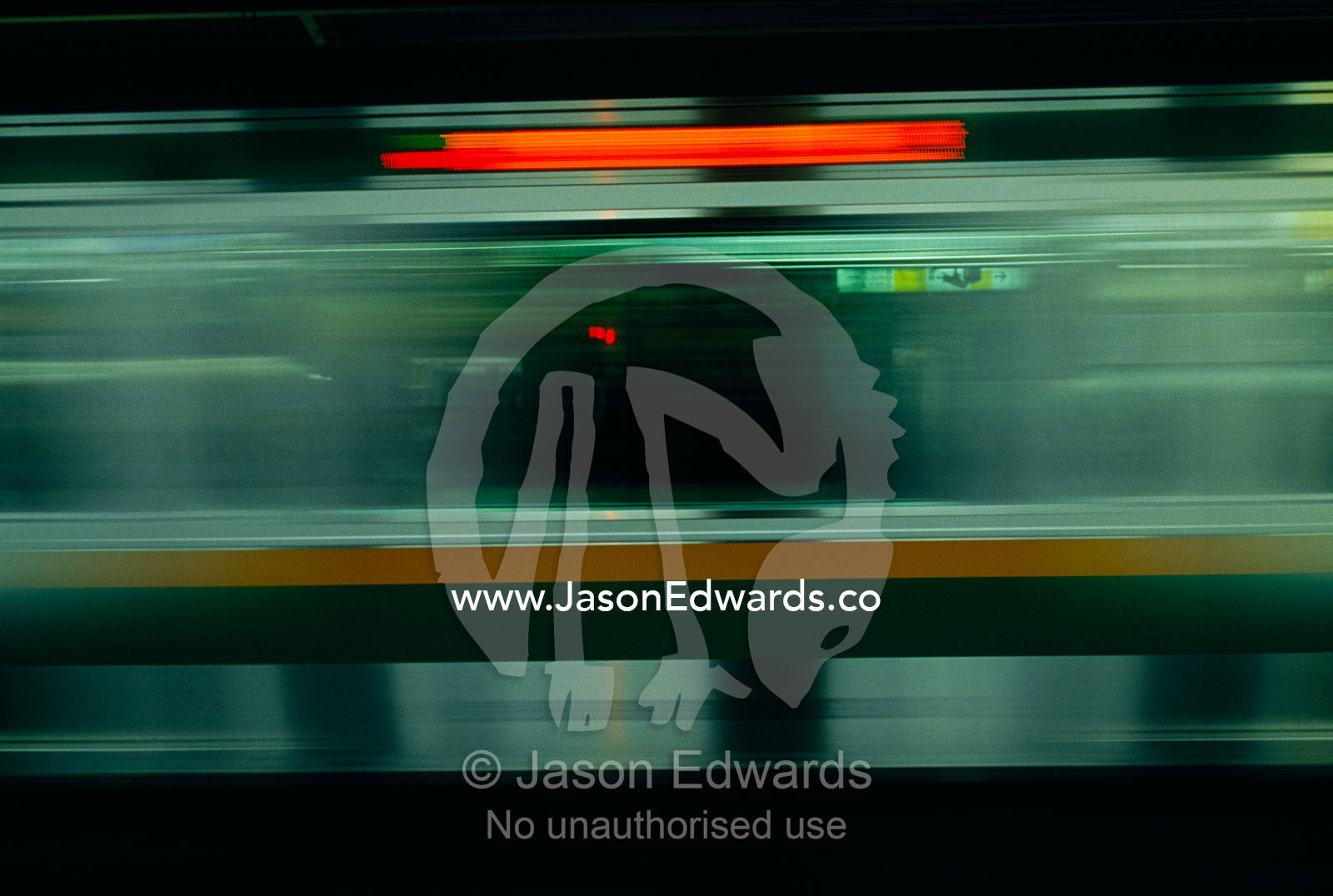 A high speed commuter train speeds between railway platforms in Tokyo. Shinjuku Station, Tokyo, Japan.