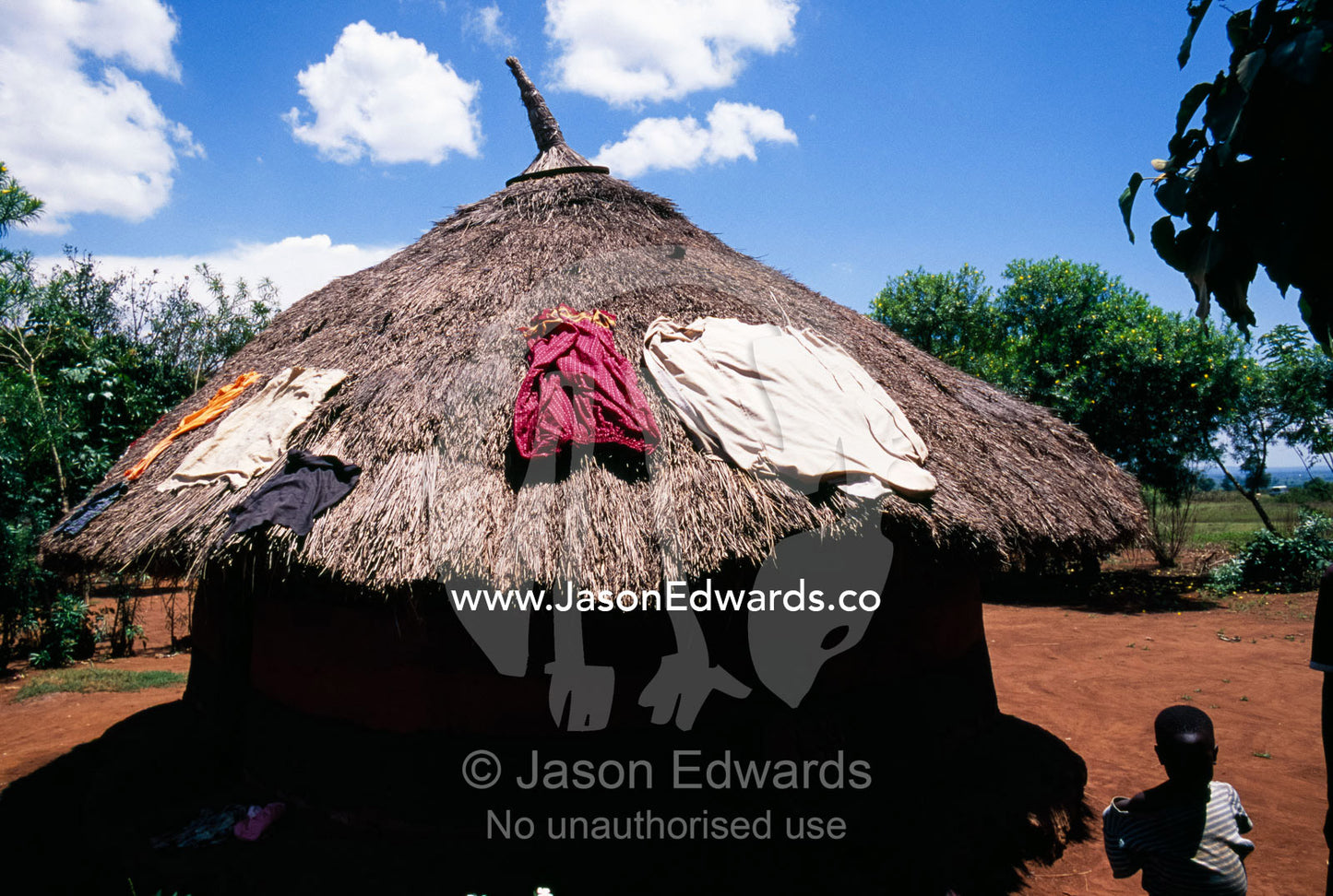 Laundry drying in the sun on the thatched roof of an African mud hut. Tororo District, Uganda.