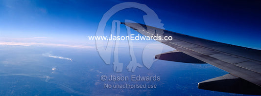 A passenger aircraft wing in flight over the USA and power stations. In flight over the United States of America, USA.