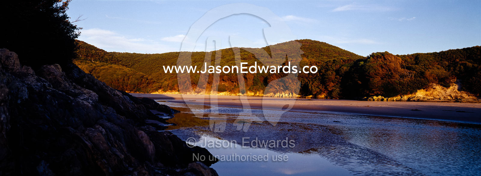 Sunset falls over coastal forest  surrounding a remote tidal inlet. South West Conservation Area, Tasmania, Australia.