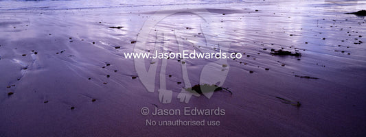 Storm clouds reflected in wet sand on a stony beach at low tide. Jan Juc, Victoria, Australia.