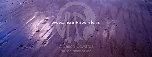 Storm clouds reflected in wet sand on a stony beach at low tide. Jan Juc, Victoria, Australia.