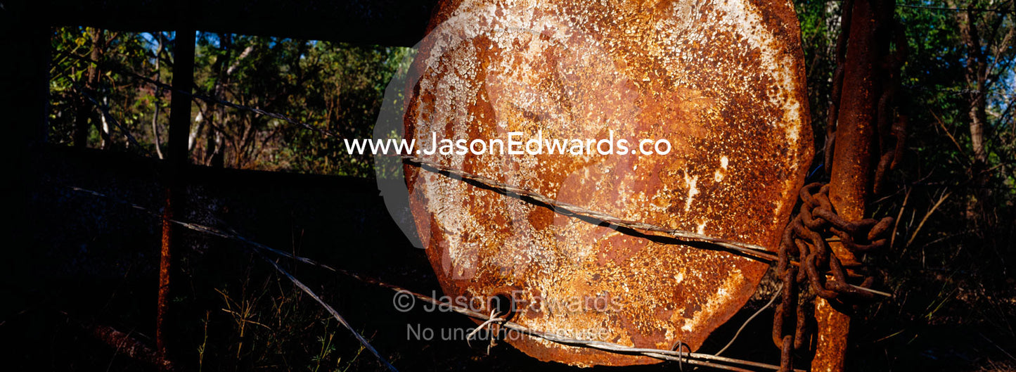 A rusting forty-four gallon drum lid mounted to a cattle station gate. Limmen National Park, Northern Territory, Australia.