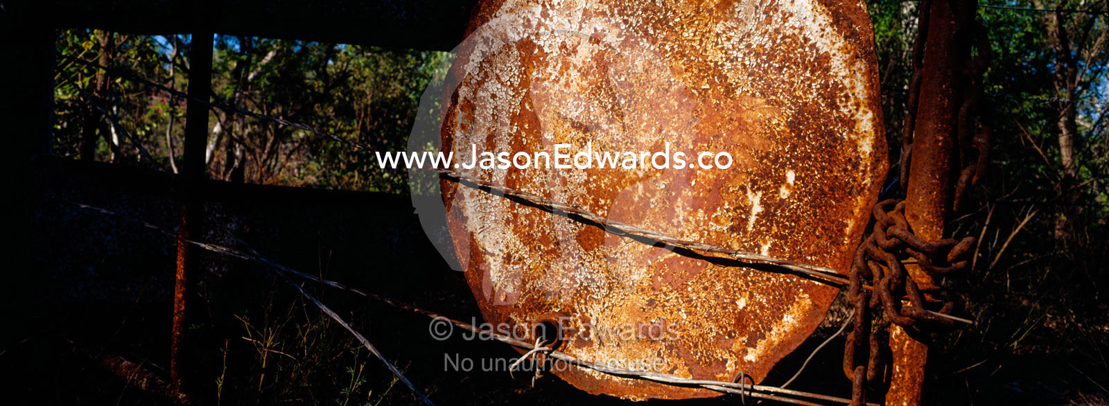 A rusting forty-four gallon drum lid mounted to a cattle station gate. Limmen National Park, Northern Territory, Australia.