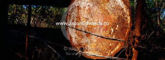 A rusting forty-four gallon drum lid mounted to a cattle station gate. Limmen National Park, Northern Territory, Australia.