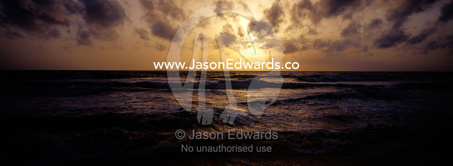 Warm waves roll onto a deserted tropical island beach at sunset. Negombo Beach, Sri Lanka.