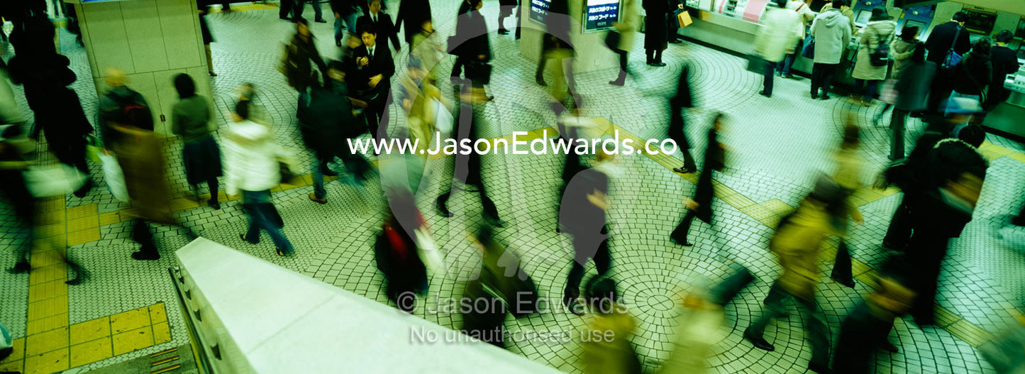 Crowds race between railway platforms to catch trains in the subway. Ikebukuro Station, Tokyo, Japan.
