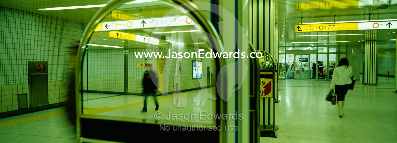Commuters, one wearing a bird flu mask, pass each other in the subway. Ikebukuro Station, Tokyo, Japan.