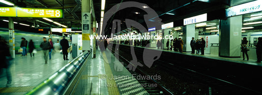 Commuters wait on railway platforms to catch trains in the subway. Ikebukuro Station, Tokyo, Japan.