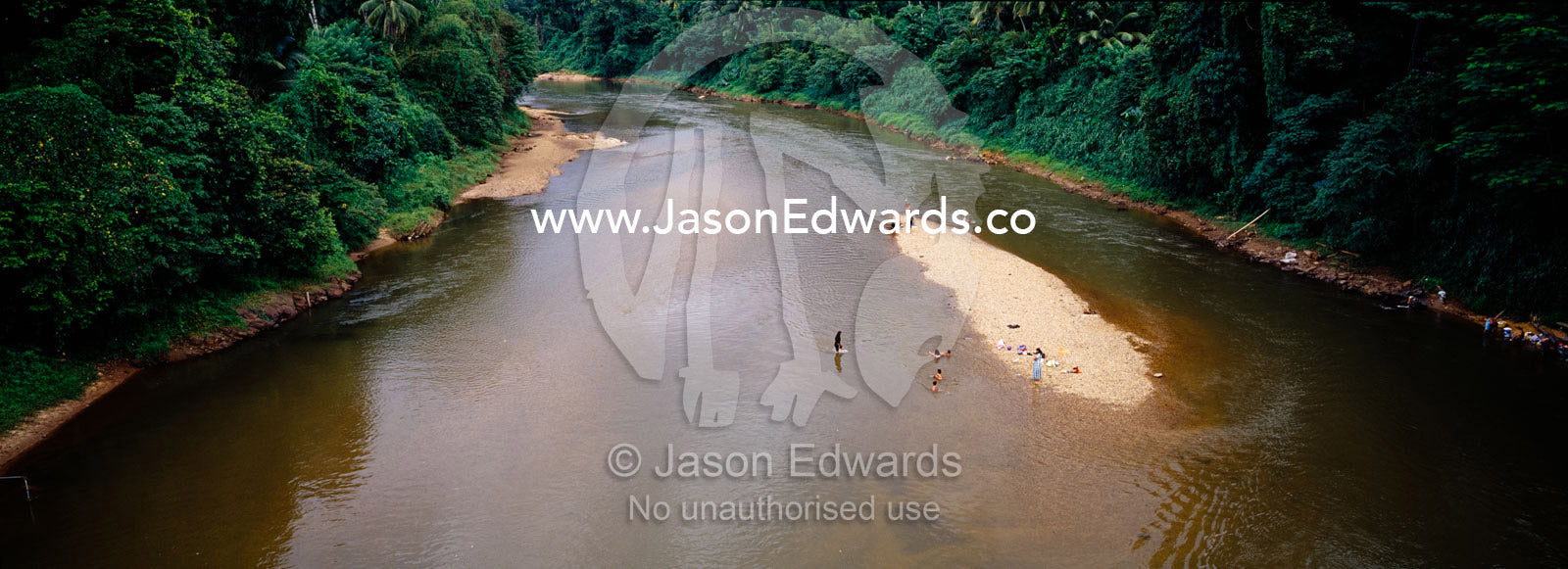 People bathe in a river wending it s way through tropical rainforest. Southern Sri Lanka.