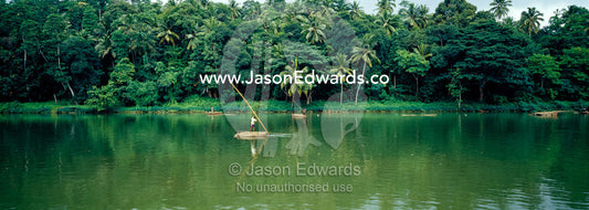Sand miners harvest sand from a river bed using long-handled shovels. Kandy, Sri Lanka.